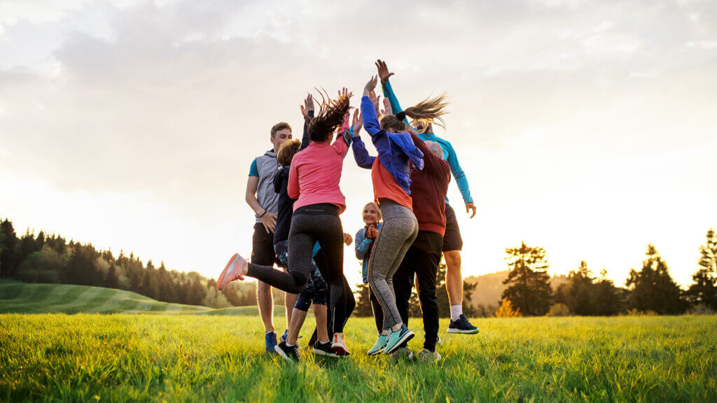 Large group of fit and active people jumping after doing exercise in nature