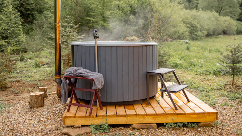 Wood-fired hot tub ready for SPA procedures on outdoor terrace in the mountains